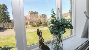 A window with a statue of a rabbit and a vase of green plants. - Castle View Cottage (Bedale)