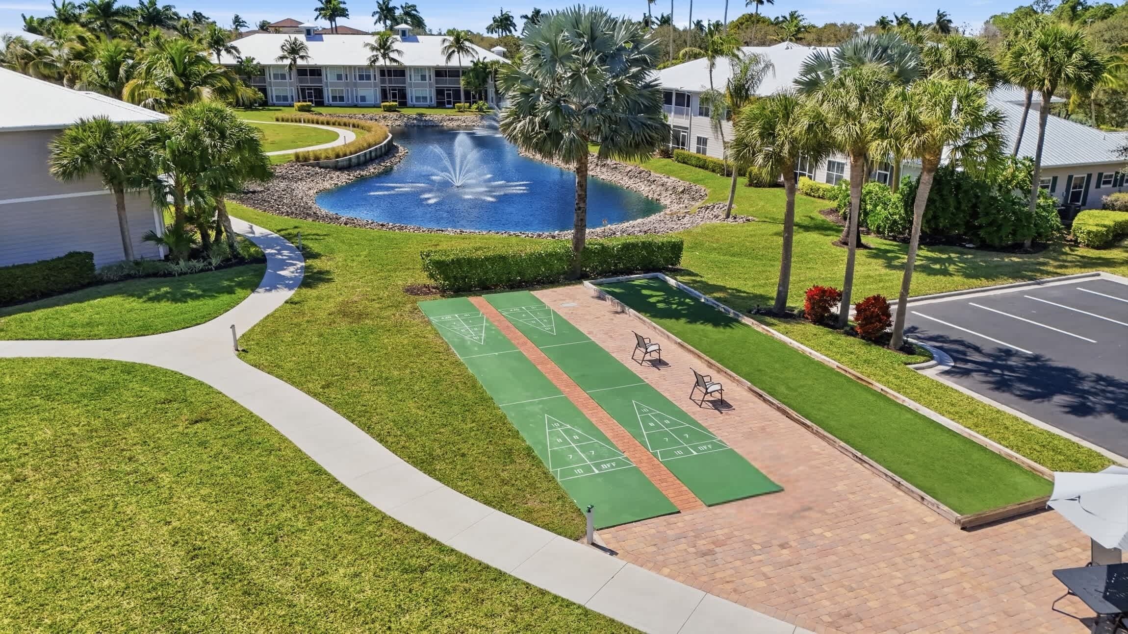 Un patio con una fuente, una cancha de shuffleboard y un estacionamiento.