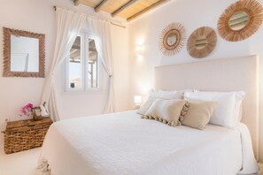 Une chambre à coucher avec un grand lit, une tête de lit en bois, un miroir et des appliques murales décoratives.