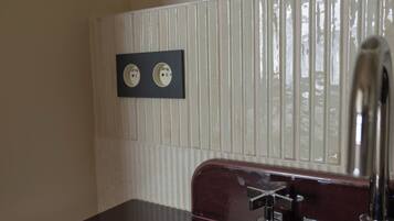 A bathroom with a marble sink, a mirror, and a bottle of lotion on the wall.
