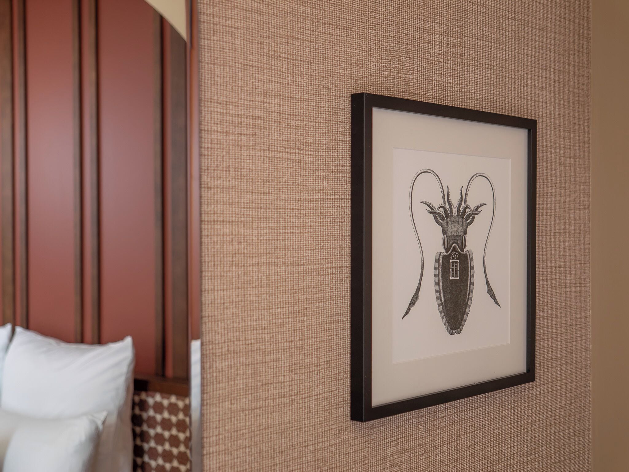 A framed artwork of a beetle on a textured wall in a hotel room.
