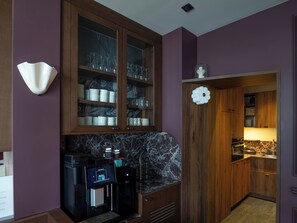 A kitchen with a coffee machine, a marble backsplash, and wooden cabinets. - Maison Atalaye - Hôtel entièrement rénové (Biarritz)