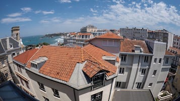 Un paisaje urbano costero con edificios que tienen techos de tejas rojas y una torre destacada.