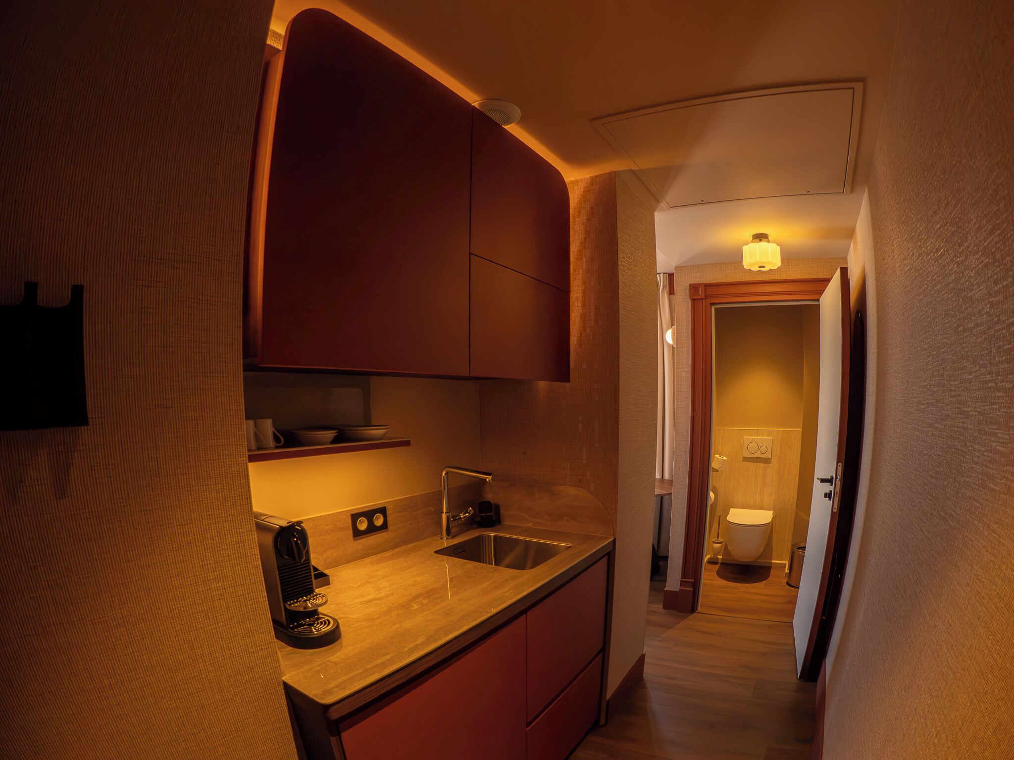 A compact kitchen with a coffee machine, a sink, and cabinets.