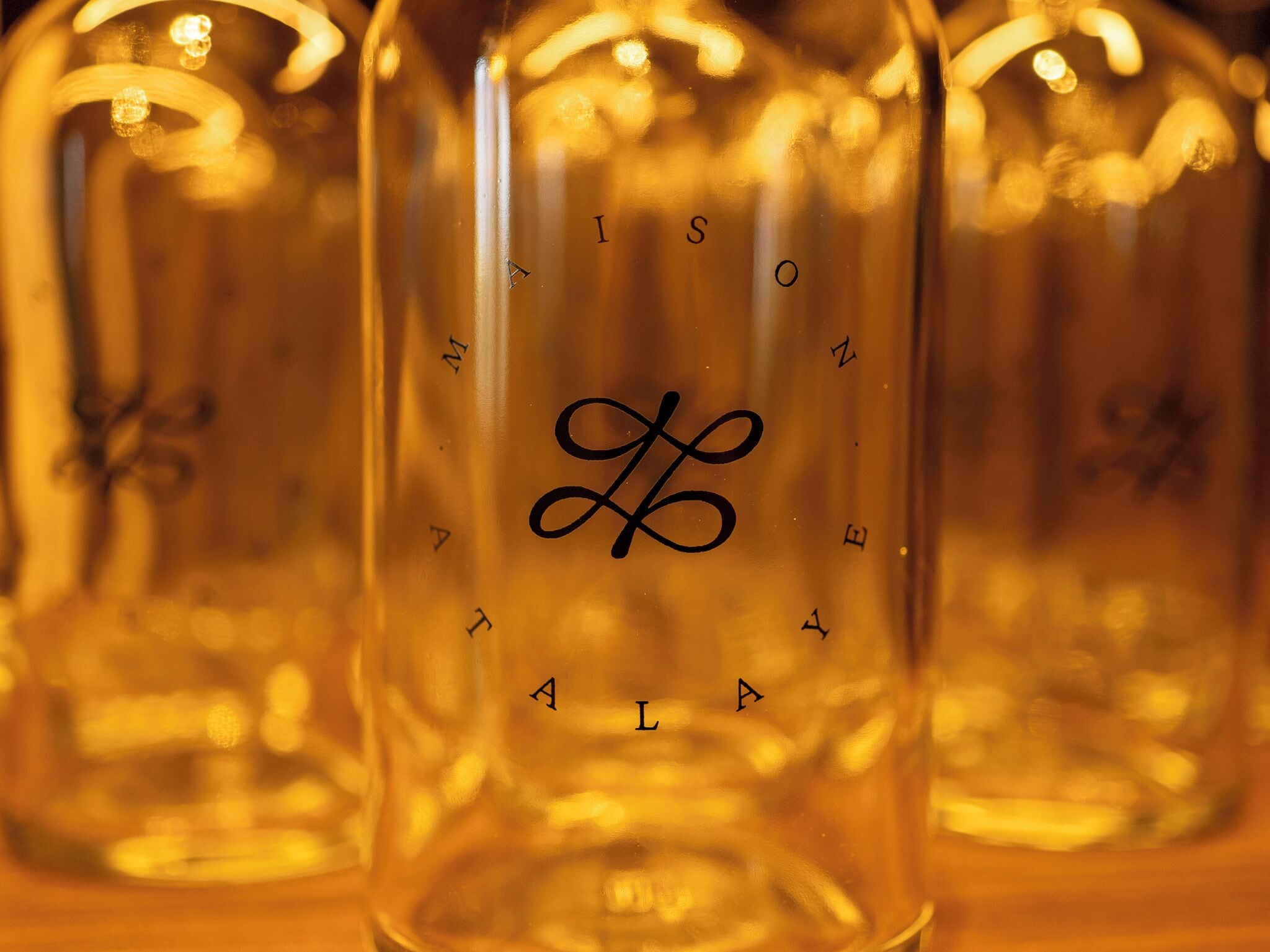 A close-up of a clear glass bottle with embossed text and a decorative symbol.