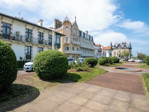 A residential street with multiple-story houses, a paved sidewalk, and parked cars.