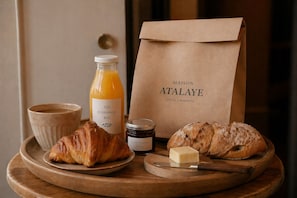 A breakfast tray with croissants, a bottle of orange juice, a jar of jam, a cup of coffee, and a block of cheese. - Maison Atalaye - Hôtel entièrement rénové (Biarritz)