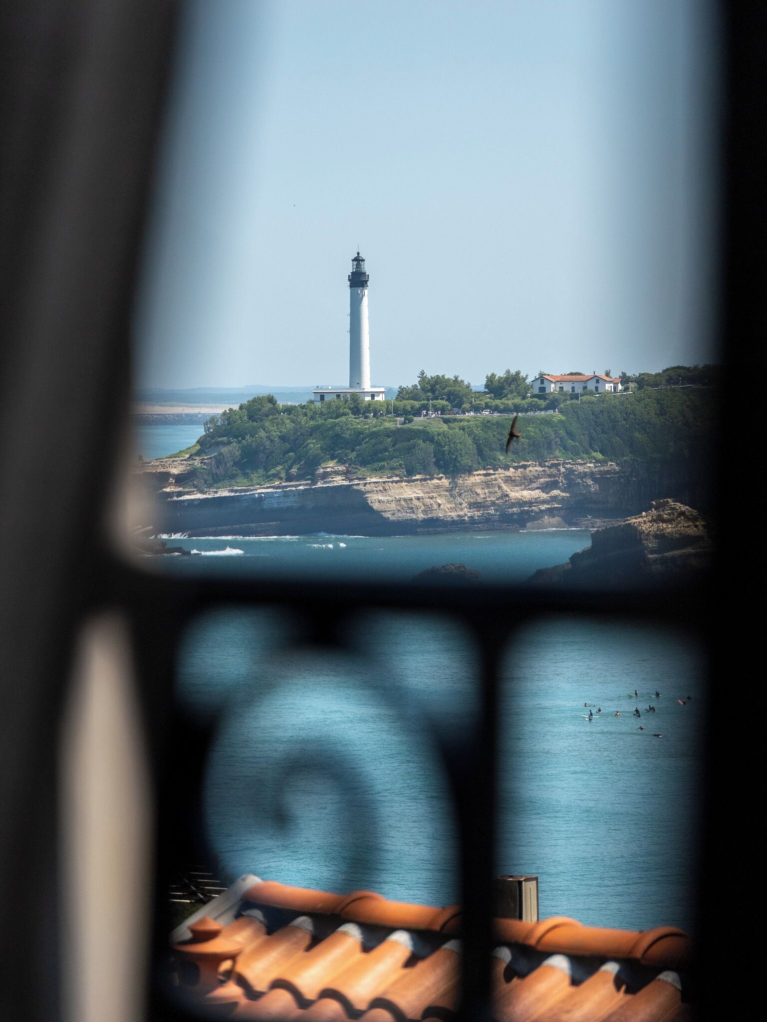 Ein Leuchtturm auf einer Klippe mit Blick auf das Meer und einem Gebäude am Ufer.