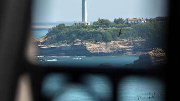 Ein Leuchtturm auf einer Klippe mit Blick auf das Meer und einem Gebäude am Ufer.