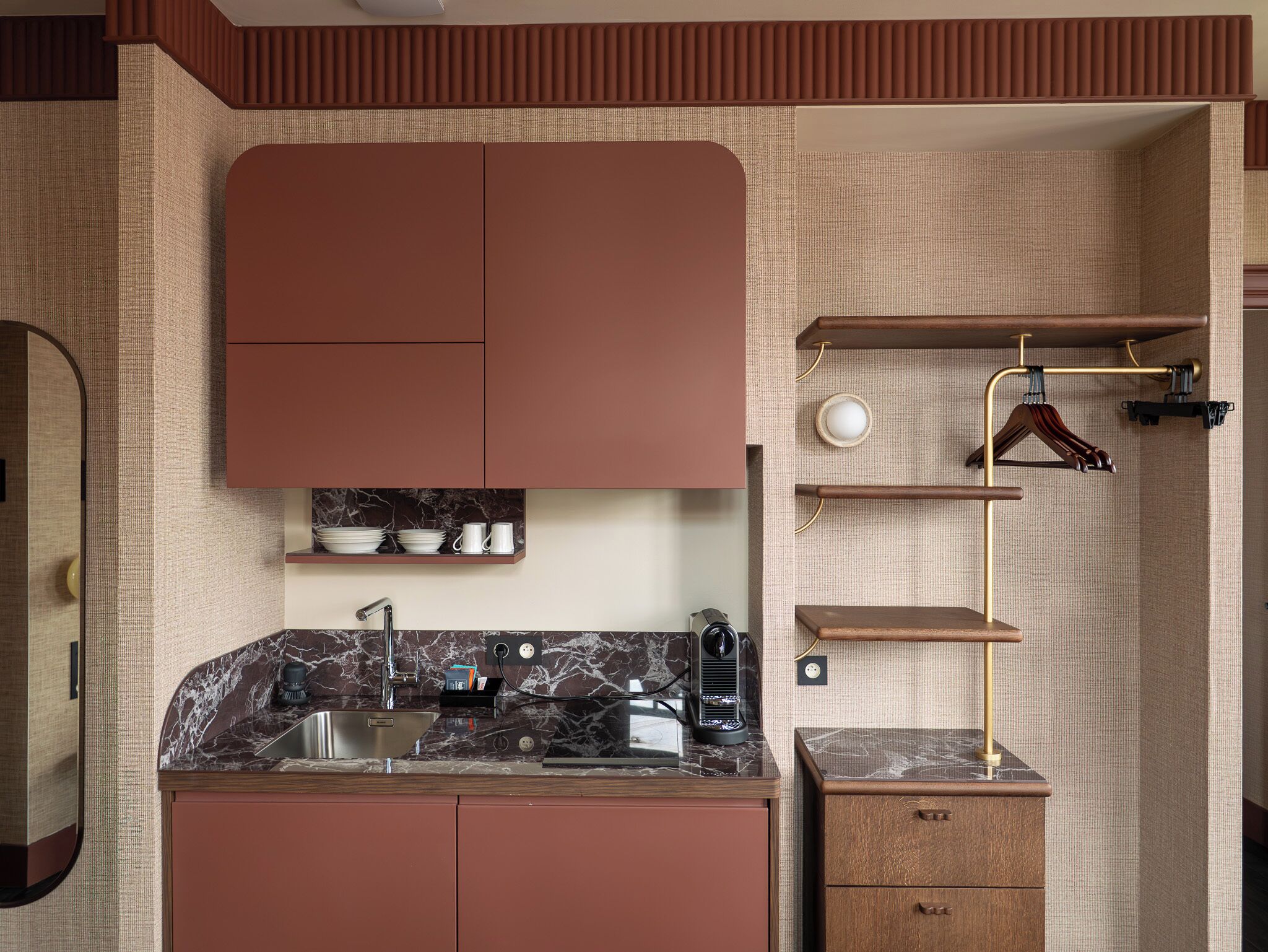Una cocina compacta con un lavamanos, una cafetera y un horno empotrado.