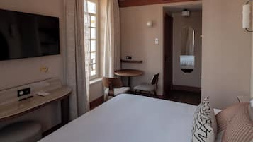 Une chambre d’hôtel équipée d’un lit, d’un bureau, d’une chaise, d’une télévision et d’une salle de bain avec un miroir.