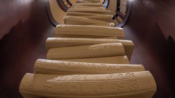 A spiral staircase with engraved steps leading upwards, surrounded by dark walls and a curved ceiling.