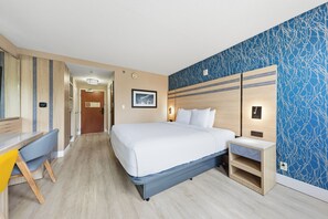 A hotel room with a bed, bedside table, desk, chair, and a blue patterned wall. - Near NYC • Refreshing Double Suite • Sleeps 4 • Pet Friendly (Carteret)