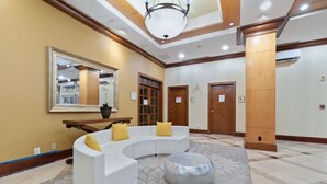 A spacious lobby with a white curved sofa, a round ottoman, a large mirror, and a wooden bench. - Near NYC • Refreshing Double Suite • Sleeps 4 • Pet Friendly (Carteret)