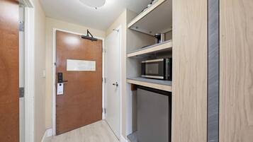 Une cuisine compacte équipée d’un four à micro-ondes, d’un petit réfrigérateur et d’un meuble en bois.