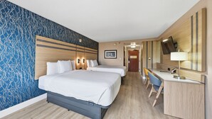 Quarto de hotel com uma cama grande, uma escrivaninha e uma cadeira. Há um espelho e um quadro na parede.