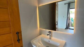 A bathroom with a white sink, a mirror, and a shower.