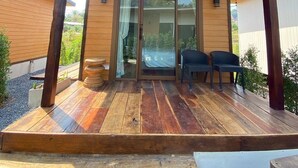 Eine Holzterrasse mit überdachtem Patio und einer Glastür sowie zwei Stühlen.