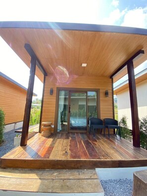 A wooden deck with a covered patio area, a sliding glass door, and two chairs. - Aonang Green Tree Pool Village (Krabi)