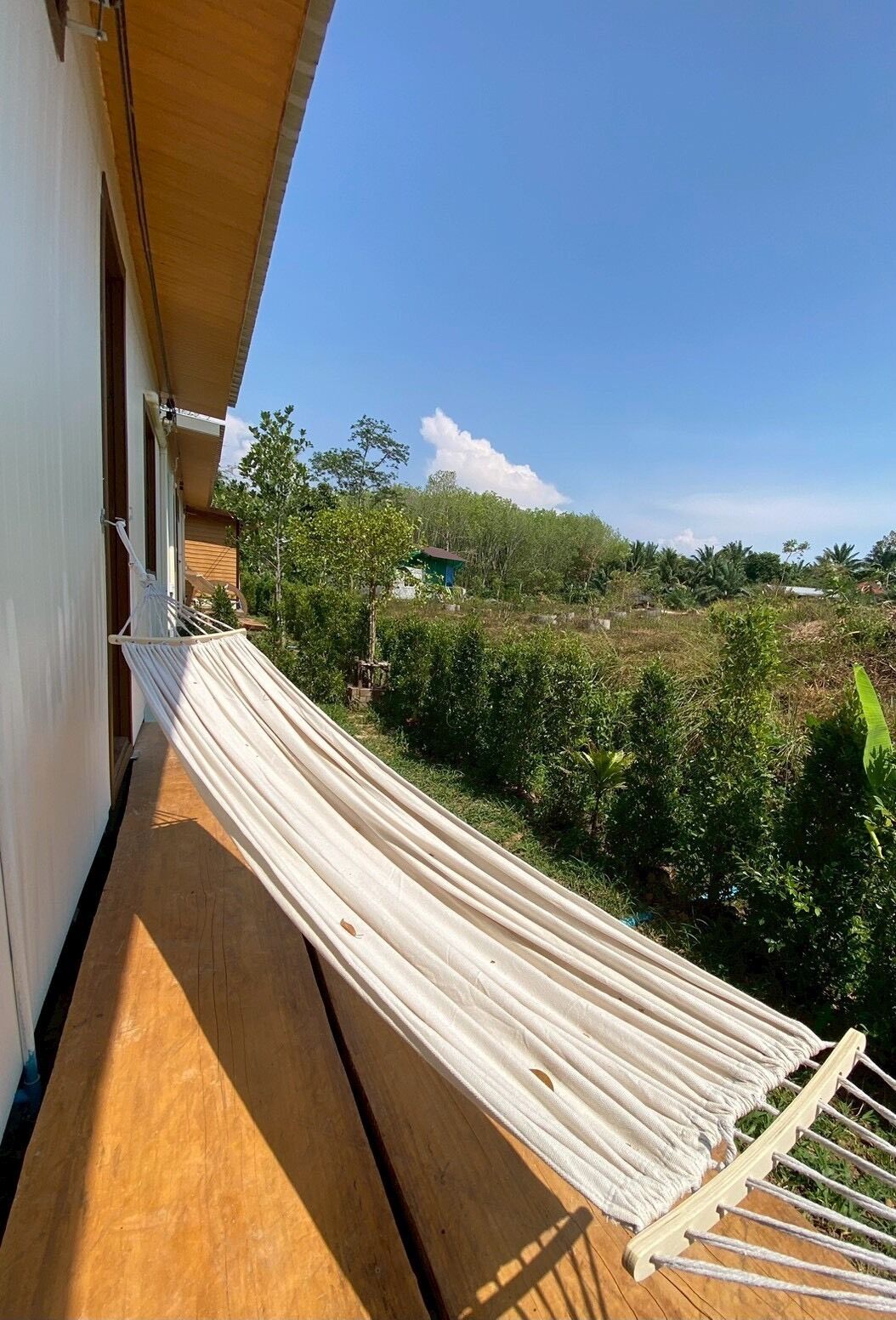Una hamaca en una cubierta de madera con vistas a un paisaje verde y un cielo despejado.