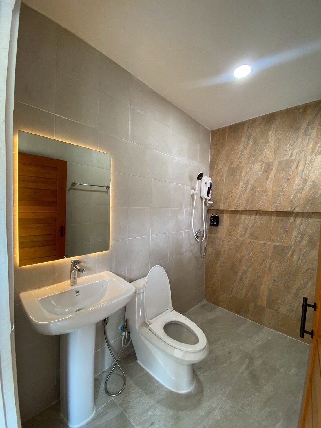 A bathroom with a sink, toilet, mirror, and shower.