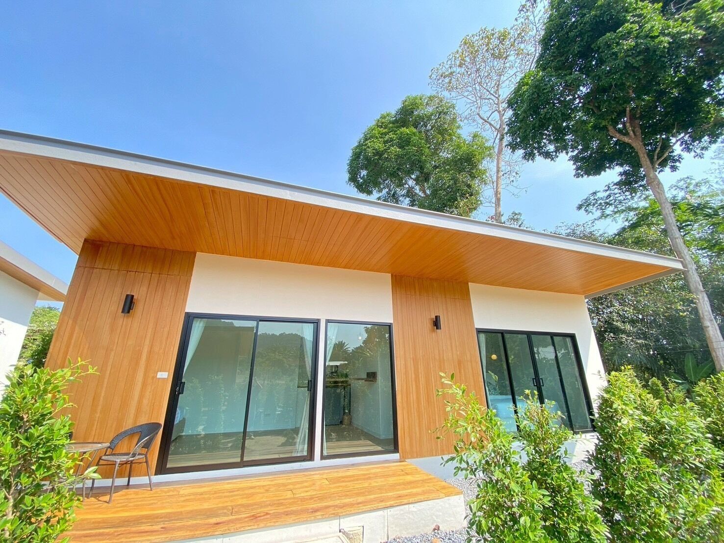 A modern house with a wooden facade, large glass windows, and a covered patio area.