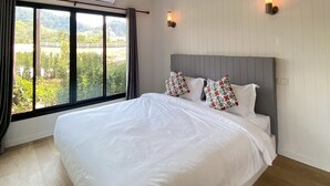Ein Schlafzimmer mit einem großen Bett, zwei Wandleuchten, einer Klimaanlage und einem Fenster mit Vorhängen.