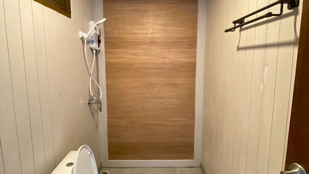 Ein kleines Badezimmer mit Toilette, Dusche und einer Wand aus Holzverkleidung.