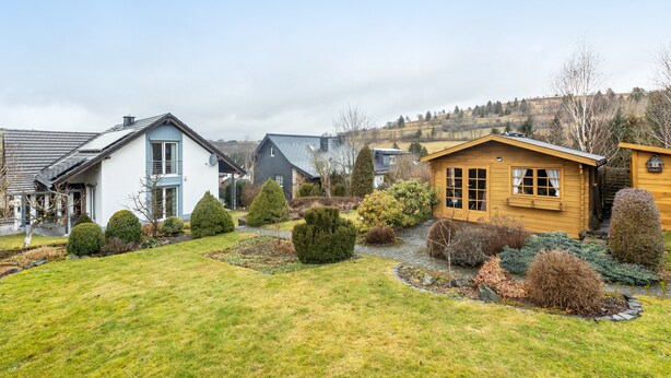 Un quartier résidentiel avec des maisons, une pelouse bien entretenue et divers arbustes.