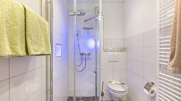 A small, modern bathroom with a glass-enclosed shower, a toilet, and a towel rack.