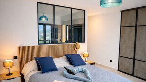Un dormitorio moderno con una cama grande, un espejo y vistas al exterior.