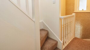 Un escalier avec des rampes blanches et des marches recouvertes de moquette.