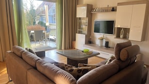 Un salon moderne comprenant un canapé, une table basse, un téléviseur et un coin repas avec des chaises.
