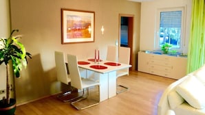 Un salon moderne avec un coin repas, une plante en pot et une fenêtre avec des rideaux.