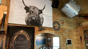 Una targa in cornice barocca, un dipinto raffigurante una testa di toro, una insegna pubblicitaria di olio motore e una targa con la scritta 'Burgers'.