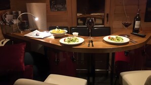 Un'area pranzo con due piatti di cibo, un bicchiere di vino, una bottiglia e una lampada.
