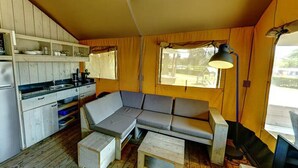 Een kleine leefruimte met een kitchenette, een bank, een tafel en een lamp.