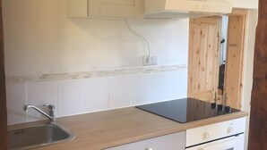 Una cucina con lavello in acciaio inossidabile, piano di lavoro in legno, pensili bianchi e backsplash piastrellato.