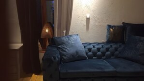 Un divano blu scuro con rivestimento trapuntato, una lampada e una parete con finitura testurizzata.