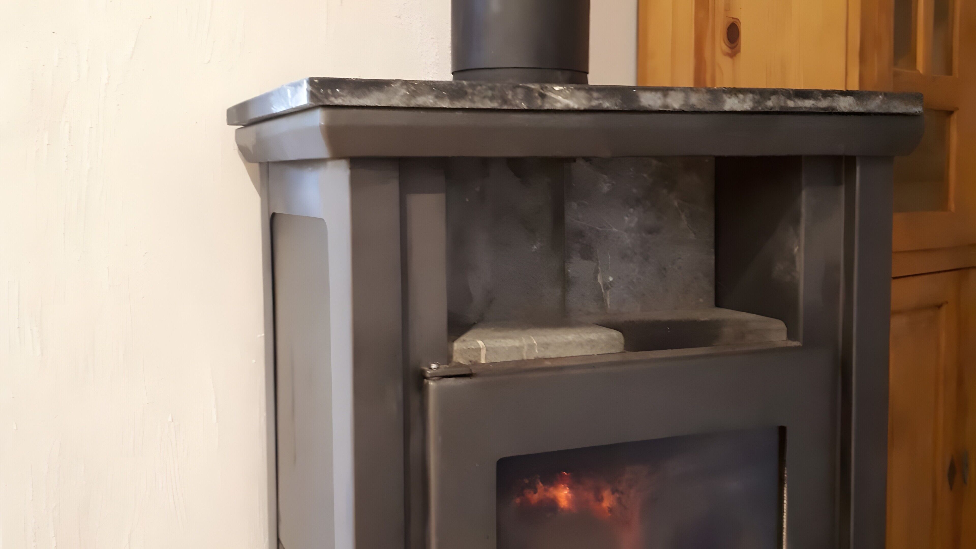 A wood-burning stove with a visible fire, a chimney, and a glass door.