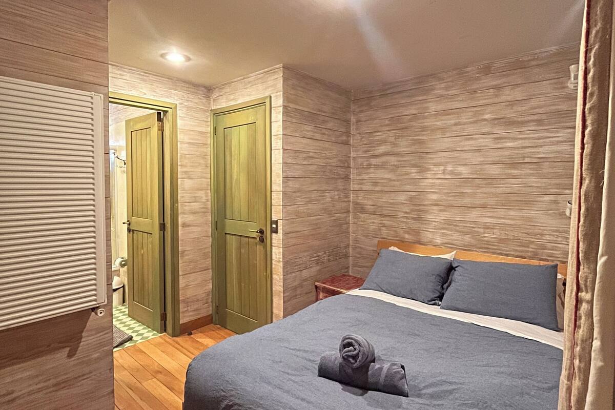 Ein Schlafzimmer mit einem hölzernen Bett, einer grünen Tür und einem Spiegel.