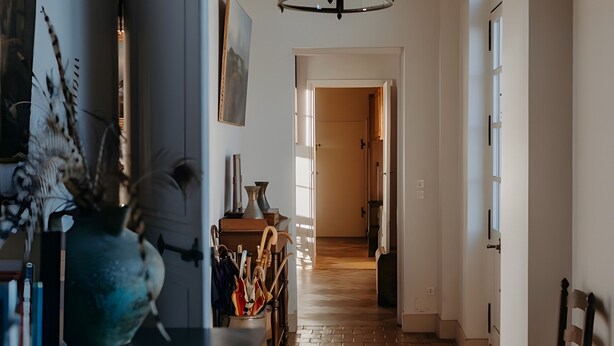 Een keuken met een donker aanrecht, een hanglamp en een houten vloer.
