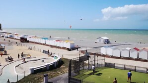 A beachside area with a fenced sports field, a small building, and a row of colorful tents. - La Maison Angèle. (Criel-sur-Mer)