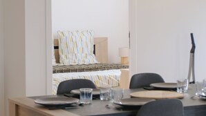 A dining area with a wooden table, black chairs, and a hanging light fixture. - La Maison Angèle. (Criel-sur-Mer)