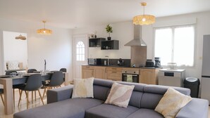 A modern kitchen with a dining area, a sofa with cushions, and pendant lighting. - La Maison Angèle. (Criel-sur-Mer)