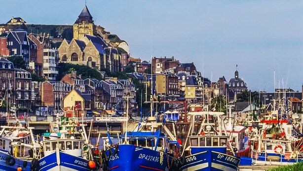 A harbor with boats docked, a historic church, and residential buildings. - La Maison Angèle. (Criel-sur-Mer)