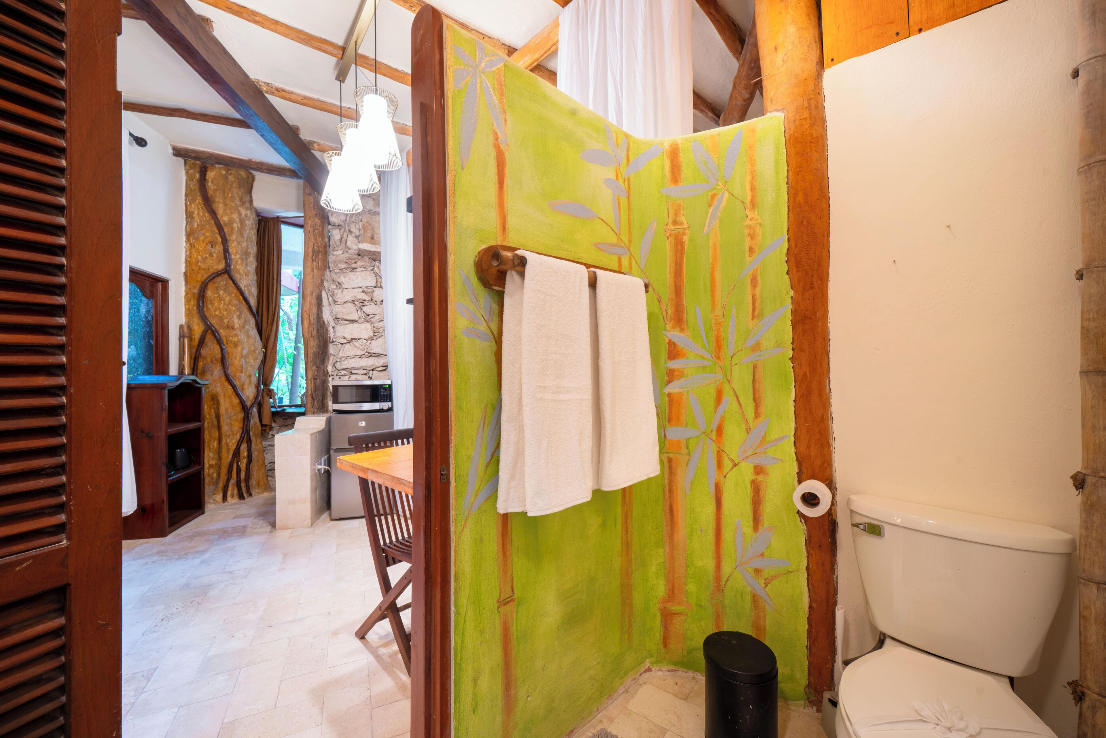 Une salle de bain avec des toilettes, un rideau de douche et une serviette accrochée au mur.