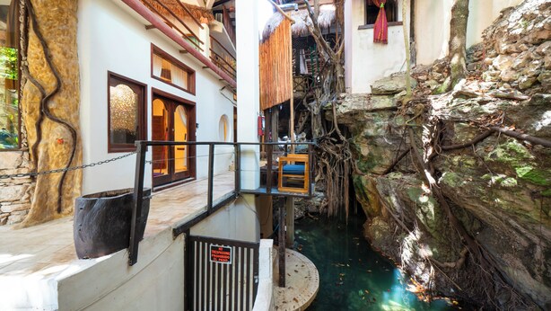 Un edificio de varios niveles con un muro de piedra, una fuente circular y una escalera de madera.