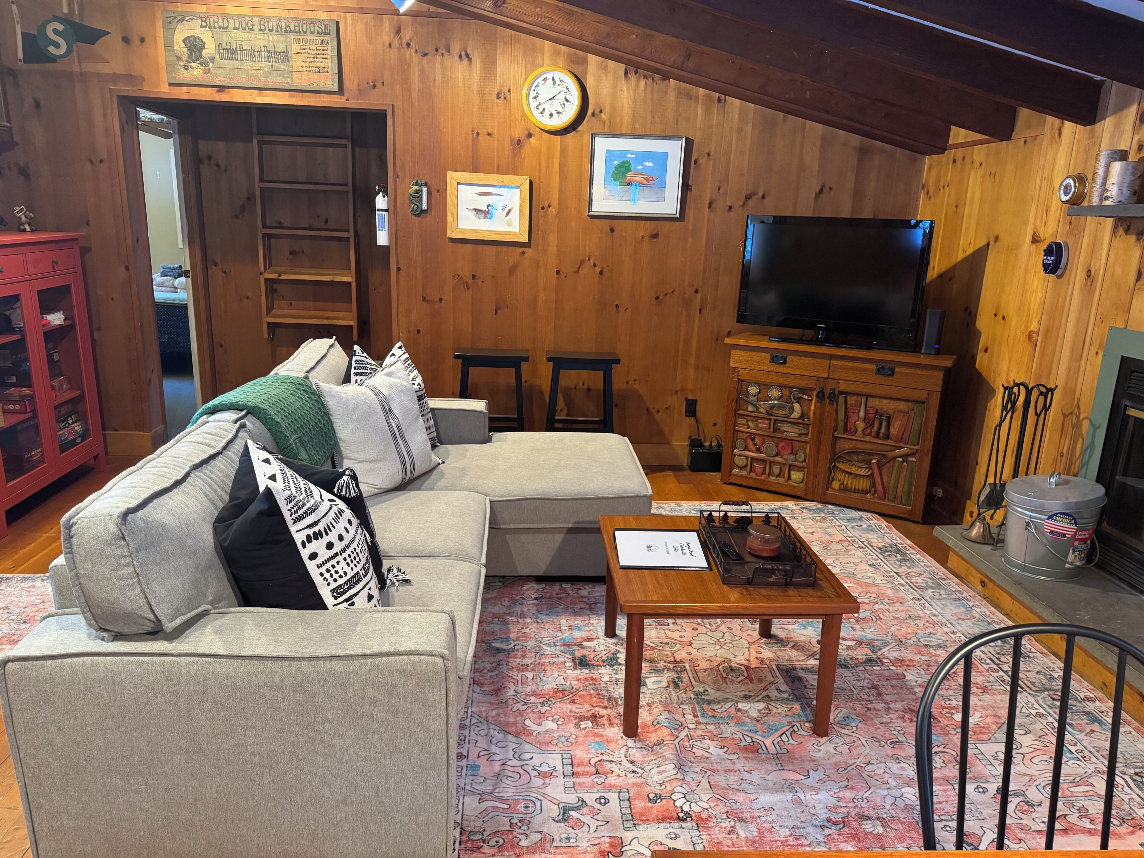 A cozy living room with a sectional sofa, a wooden cabinet, a television, and a fireplace.