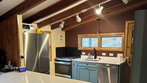 A kitchen with a central island, bar stools, a stove, and a refrigerator.